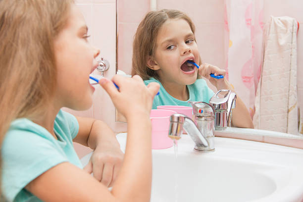 6 歳の少女をきれいにして、下の横の歯 - smiling human teeth toothbrush moving up ストックフォトと画像