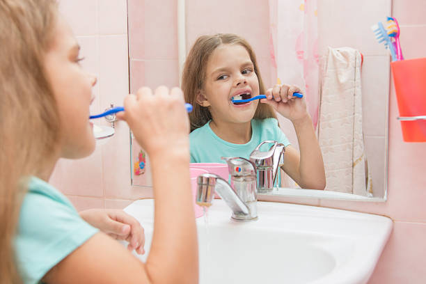 jeune fille de six an nettoie les dents look latérale de la tige - smiling human teeth toothbrush moving up photos et images de collection