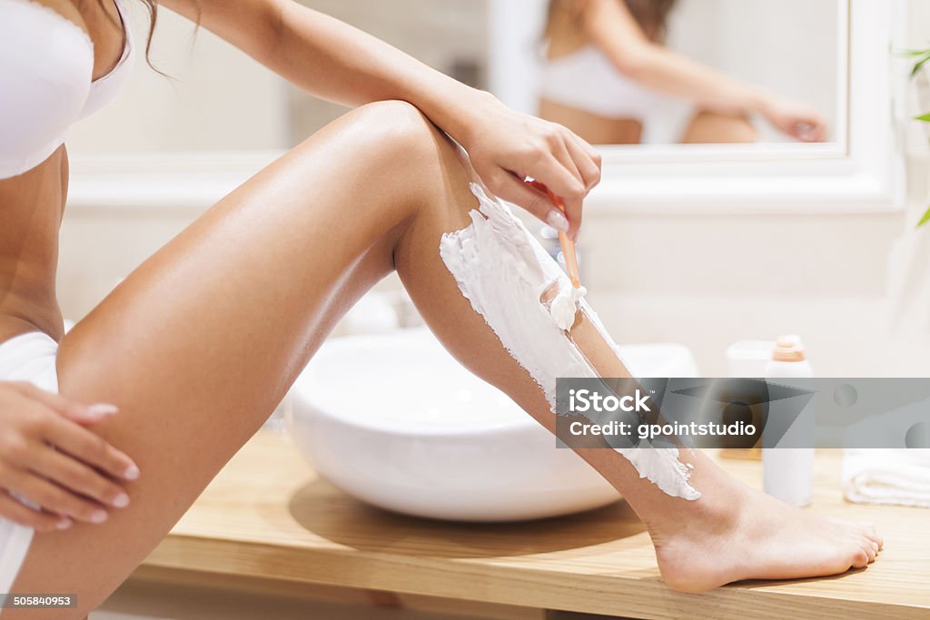 Close up of woman shaving legs in bathroom Women Stock Photo