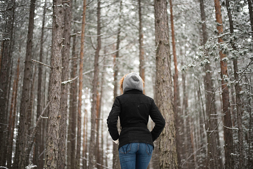 Portrait of woman hiking thru forest while snowing,grain added