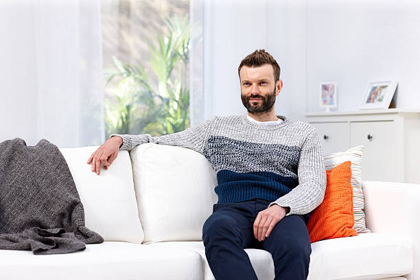 istock Happy young man sitting on couch at home 505842901