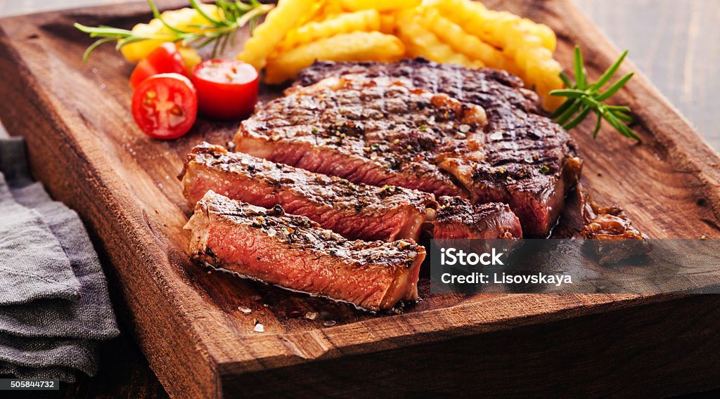 Sliced Steak Ribeye with french fries Sliced Steak Ribeye with french fries on serving board block on wooden background Steak Stock Photo