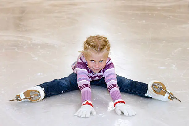 Photo of The little girl sitting on ice in ice skating.