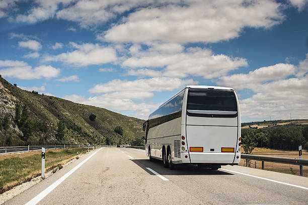 Coach, long haul bus, drives through Spain A white coach, or long haul bus for tourists drives through the open roads of Spain, Europe on a summer day. There are white clouds against a blue sky and countryside. coach bus photos stock pictures, royalty-free photos & images