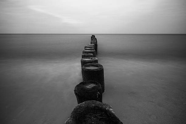 istock breakwater on the beach, black and white 505864278