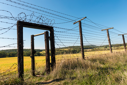 Ćižov, Czech Republic - October 2, 2015: Open doors as part of the Iron Curtain at Ćižov in the middle of a green field. Clear blue sky in background. Low angle view. 