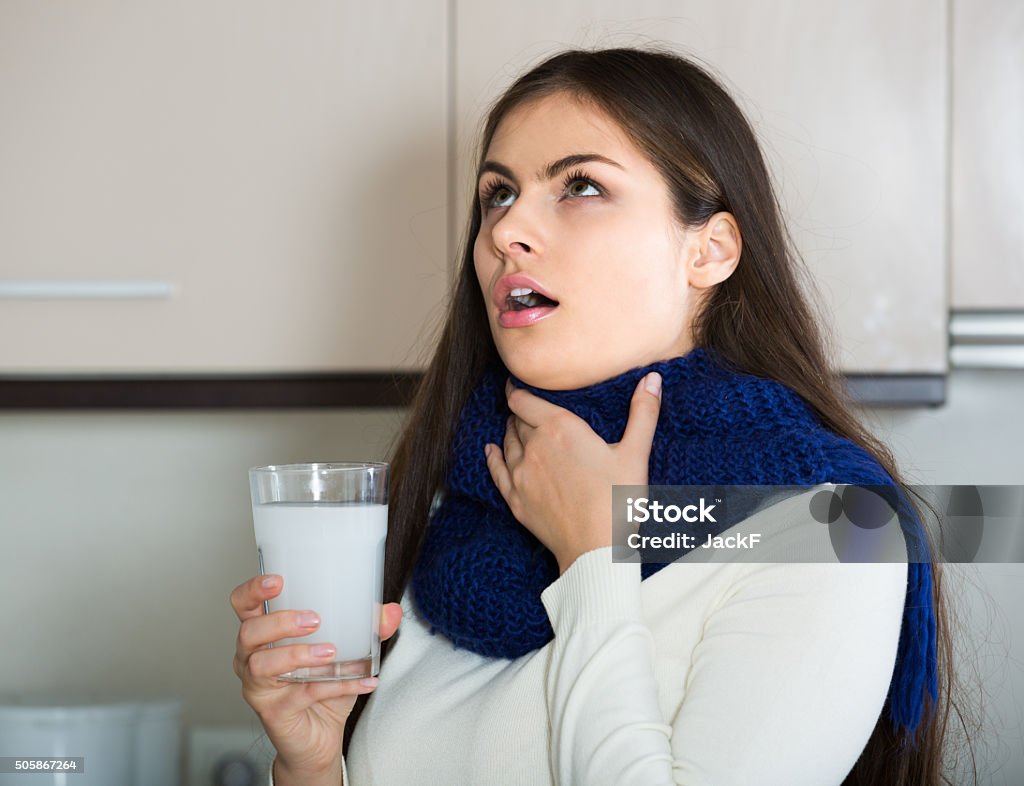 Girl with throat pain gargling throat in  kitchen Girl with throat pain gargling throat in domestic kitchen Gargling Stock Photo