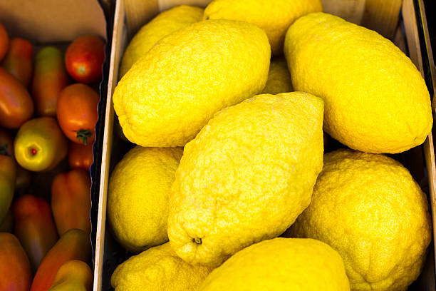 Bright big citrons (close-up) at a farmer's market. Tomatoes on one edge. Shot in Sicily, Italy.