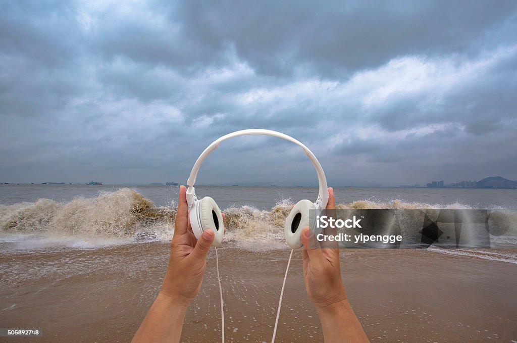 hand holding earphone on beach,listening to waves Noise Stock Photo