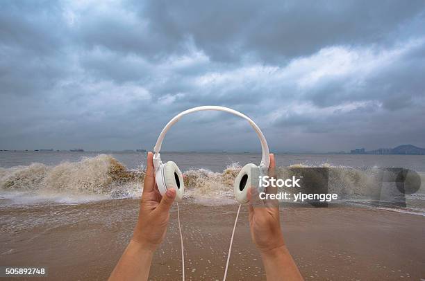 Hand Holding Earphone On Beachlistening To Waves Stock Photo - Download Image Now - Noise, Listening, Arts Culture and Entertainment