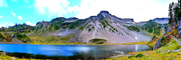 Bagley Lake Panorama View,Mt Baker Mount Baker , also known as Koma Kulshan or simply Kulshan, is an active glaciated andesitic stratovolcano  in the Cascade Volcanic Arc and the North Cascades of Washington in the United States. Mount Baker has the second-most thermally active crater in the Cascade Range after Mount Saint Helens. About 31 miles (50 km) due east of the city of Bellingham, Whatcom County, Mount Baker is the youngest volcano in the Mount Baker volcanic field. While volcanism has persisted here for some 1.5 million years, the current glaciated cone is likely no more than 140,000 years old, and possibly no older than 80-90,000 years. Older volcanic edifices have mostly eroded away due to glaciation. picture lake stock pictures, royalty-free photos & images