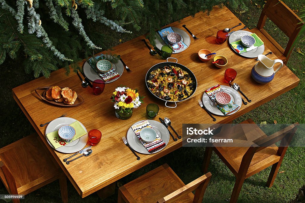 spanish style dining table with paella Spanish style dining table with paella and  Spanish style dishes on wooden table in backyard. Overview. Dining Table Stock Photo