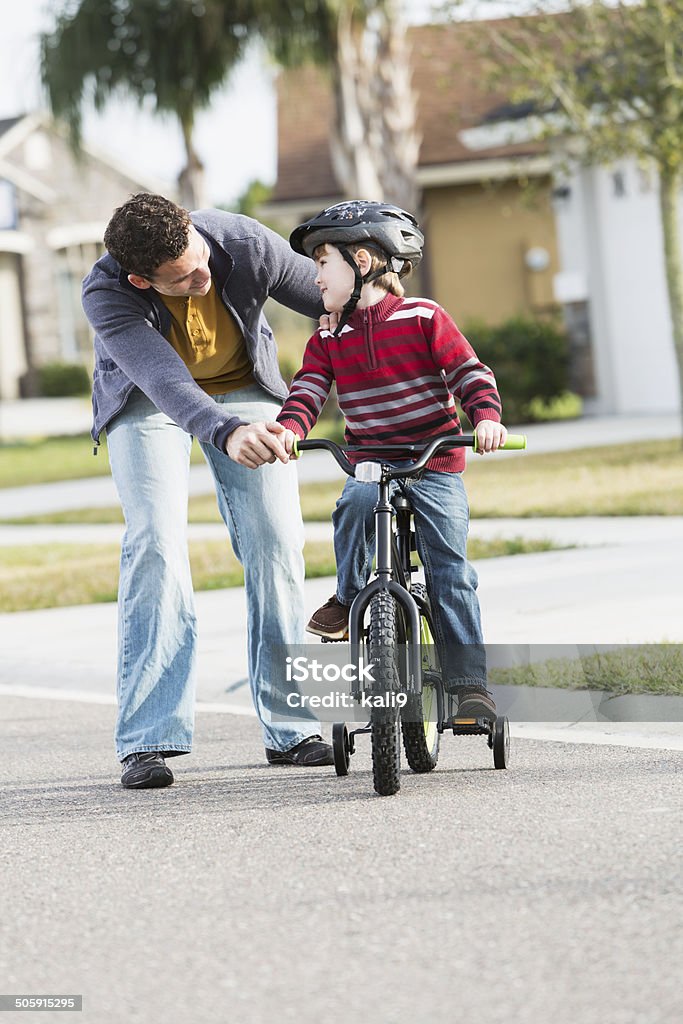 Learning to ride bicycle Father (20s) helping son (4 years) learn to ride bicycle. Cycling Stock Photo