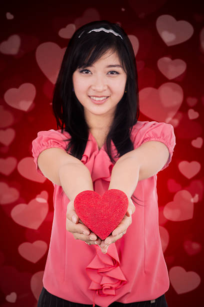 istock Chinese girl holds a gift with heart background 505916604