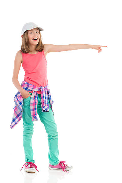 A silhouette of a young girl is seen posing on a stone \npillar on stage. She holds her dance cane in her hand \nand wears a top hat.