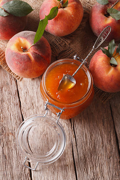 istock Fresh peach jam in glass jar closeup. vertical top view 505917458