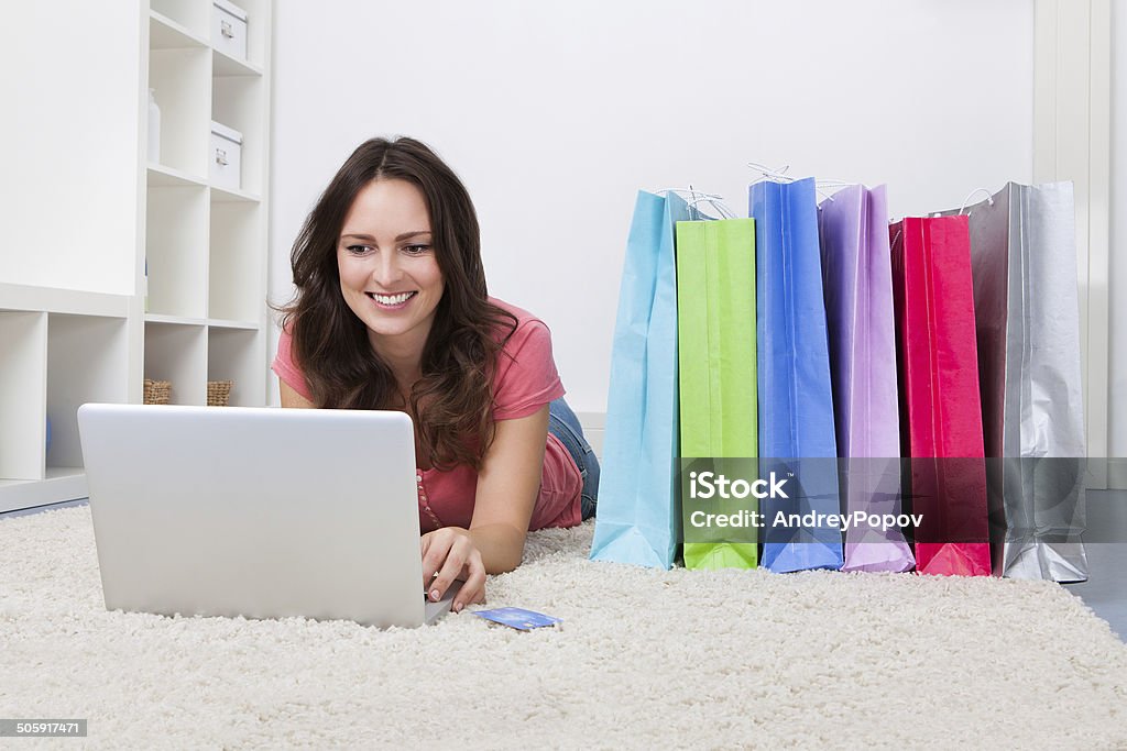 Woman With Shopping Bags And Credit Card Smiling Young Woman Lying On Carpet Besides Row Of Shopping Bags Adult Stock Photo