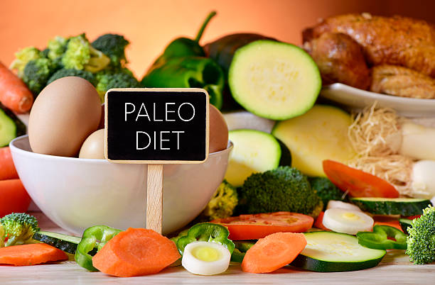 eggs, chicken, vegetables and text paleo diet closeup of a signboard with the text paleo diet on a table full of different raw vegetables, a bowl with some chicken eggs and a chicken paleo diet photos stock pictures, royalty-free photos & images