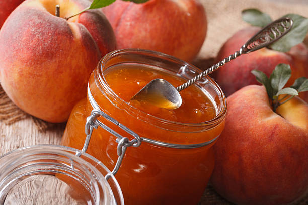 istock Peach jam in glass jar closeup on the table. Horizontal 505918578