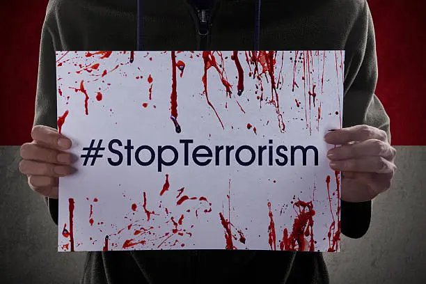 Photo of anonymous person holding a paper with #stopterrorism in front of Indonesian flag