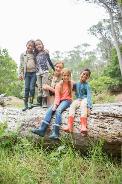 istock Students and teacher smiling on wooden log 505935897