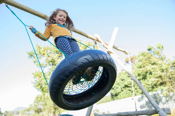 girl playing on tire swing - tire swing imagens e fotografias de stock