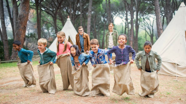 children having sack race at campsite - elementary age child group of people togetherness imagens e fotografias de stock