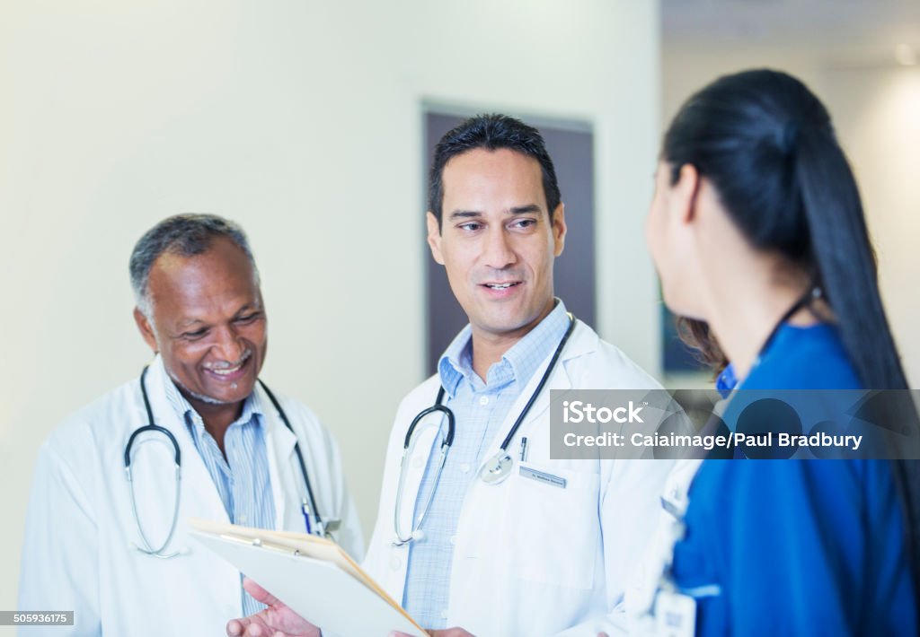 Doctors and nurse talking in hospital hallway  30-34 Years Stock Photo
