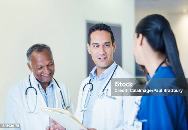 Doctors And Nurse Talking In Hospital Hallway Stock Photo - Download Image Now - 30-34 Years, 30-39 Years, 40-44 Years