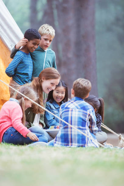istock Students and teacher reading at campsite 505936325