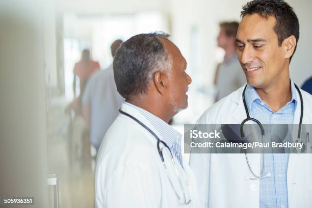 Doctors Talking In Hospital Hallway Stock Photo - Download Image Now - Doctor, Talking, 30-39 Years