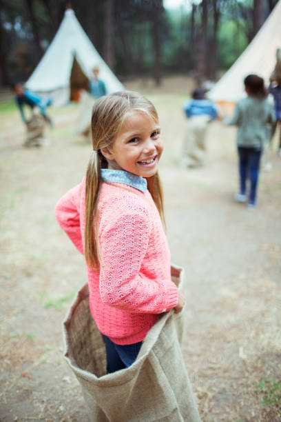 девушка улыбается в мешке в кемпинге - child playing sack race sports race стоковые фото и изображения