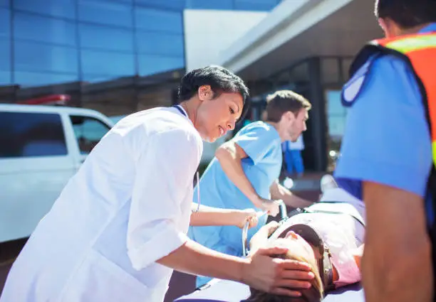 Photo of Doctor, nurse and paramedics wheeling patient to hospital