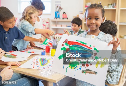 istock Student showing off finger painting in classroom 505936773