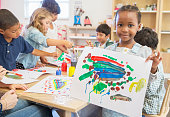 istock Student showing off finger painting in classroom 505936773