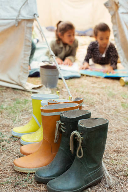 レインブーツはキャンプ場のテントの外に並んだ - kid reading ストックフォトと画像