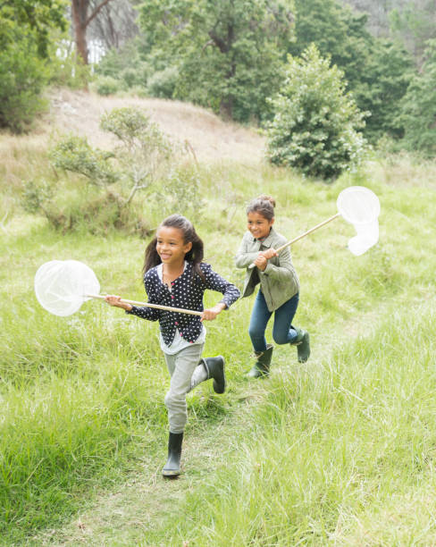 Little girl running and catching butterflies with a net isolated on white background