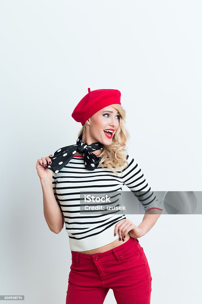 Excited blonde french woman wearing red beret Portrait of excited beautiful blonde woman in french outfit, wearing a red beret, striped blouse and neckerchief, looking away with mouth open. Adult Stock Photo