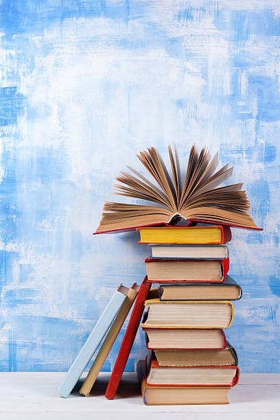 istock Stack of colorful hardback books, open book on blue background 505944058