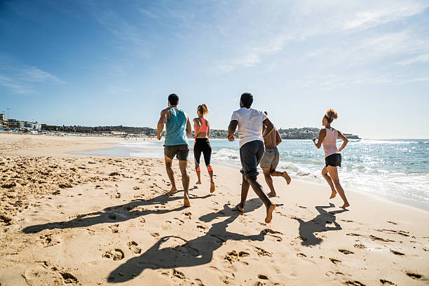 Group of fit people running at the beach Group of fit people running at the beach and enjoying the summer sports training australia stock pictures, royalty-free photos & images