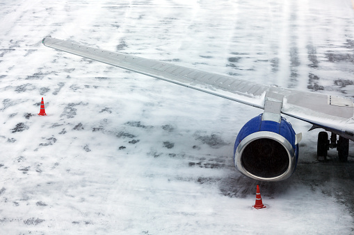 Passenger Airplane on the airfield winter before takeoff. Sleeve for boarding passengers in the aircraft
