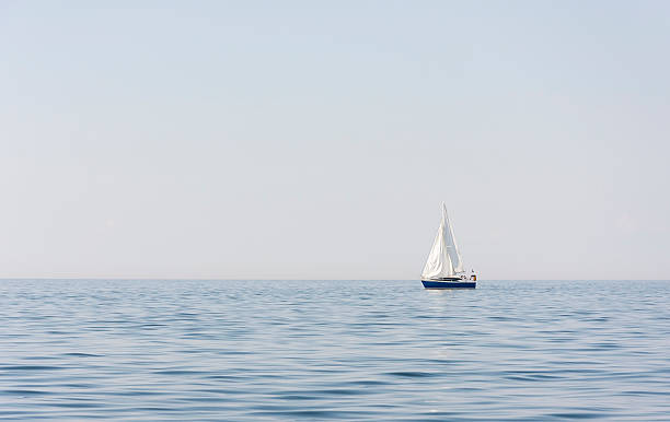 голубой парусные лодки на море и видом на океан - sea water single object sailboat стоковые фото и изображения