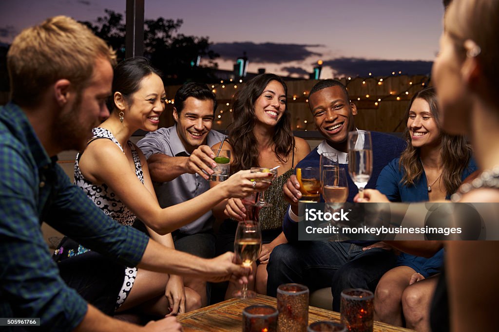 Gruppo di amici godendo serata al Bar sul tetto - Foto stock royalty-free di Tetto