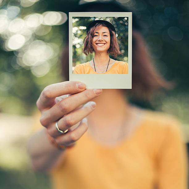 Girl holding instant selfie Teenage girl showing instant photo selfie in front of photos stock pictures, royalty-free photos & images