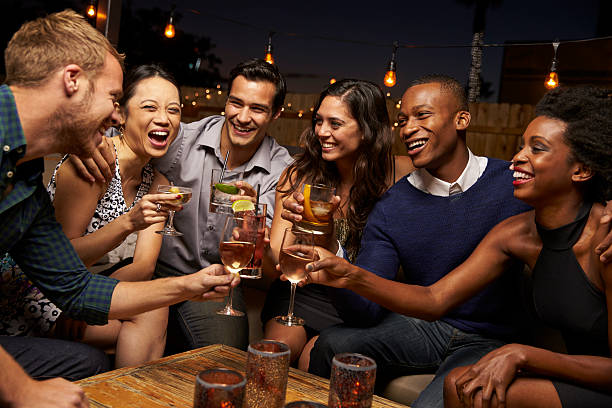 Group Of Friends Enjoying Night Out At Rooftop Bar Group Of Friends Enjoying Night Out At Rooftop Bar drinking stock pictures, royalty-free photos & images