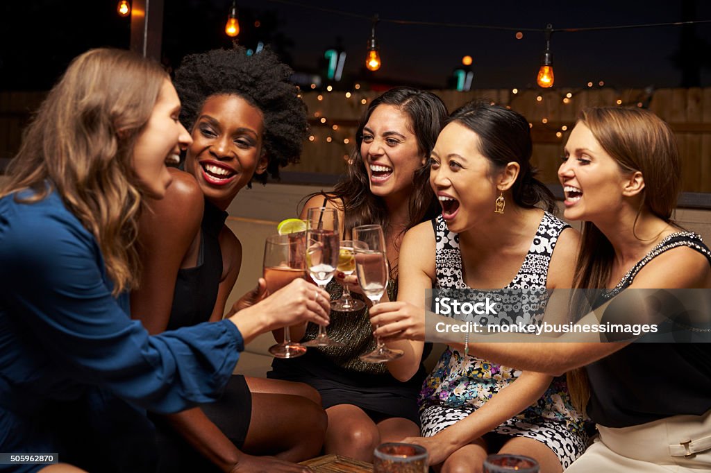 Group Of Female Friends Enjoying Night Out At Rooftop Bar Women Stock Photo