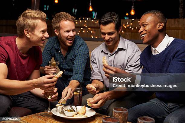 Macho Grupo De Amigos Disfrutando De Noche En El Bar Del Último Piso Foto de stock y más banco de imágenes de Sólo hombres