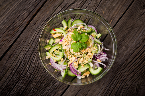 Homemade DIY natural thai green cucumber salad with red onion, sweet sauce, coriander, chilli and peanuts