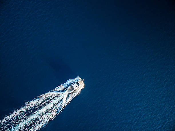 Speedboat racing along the open sea Fast speedboat racing along the open sea leaving white trail. High angle view from drone (quadcopter) Phantom 3. nautical vessel stock pictures, royalty-free photos & images