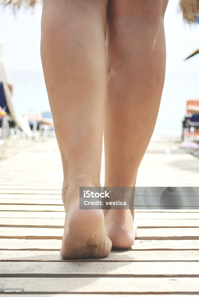 Walk to the sea view of nice smooth womanâs legs on sandy sunny beach Adult Stock Photo